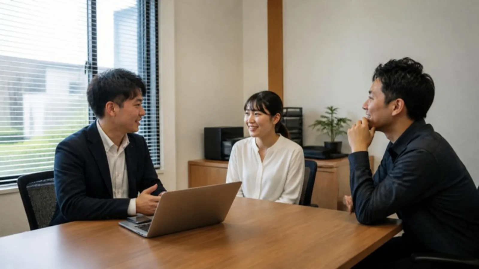 小さな事務所で打ち合わせをする3人の社員